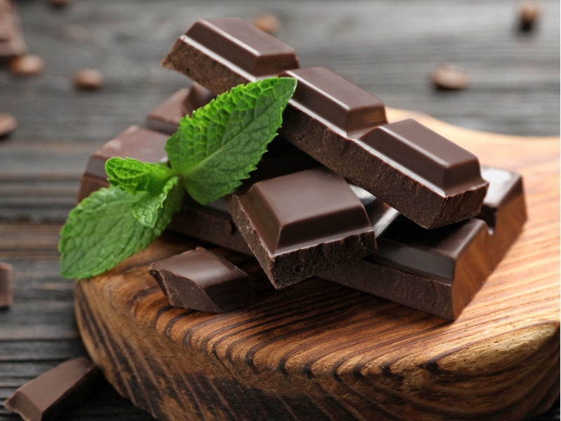 Dark Chocolate Tablets with Mint Leaves  on a Wooden Cutting Board