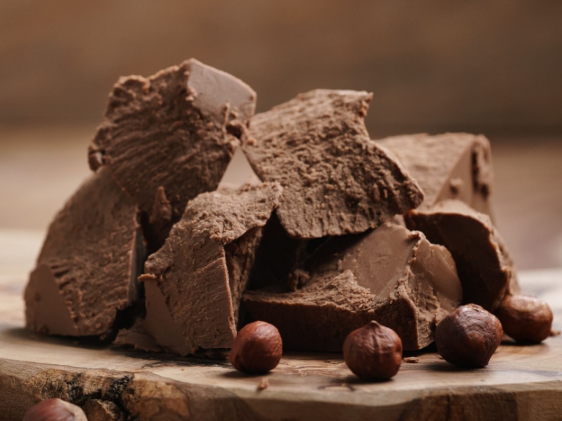 Chunks of Gianduja Chocolate with Hazelnut on a Wooden Cutting Board