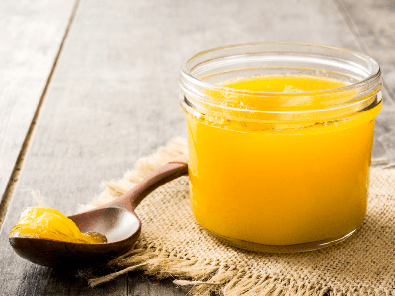 Homemade Ghee on a Small Glass and Scooped Wooden Spoon