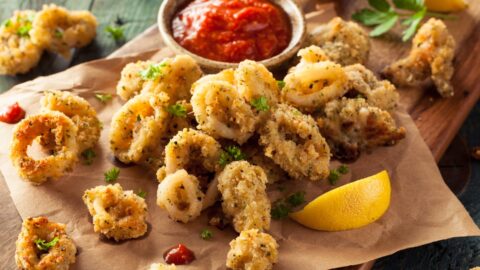 Homemade Deep Fried Calamari with Marinara, Lemon and Herbs in a Wooden Board