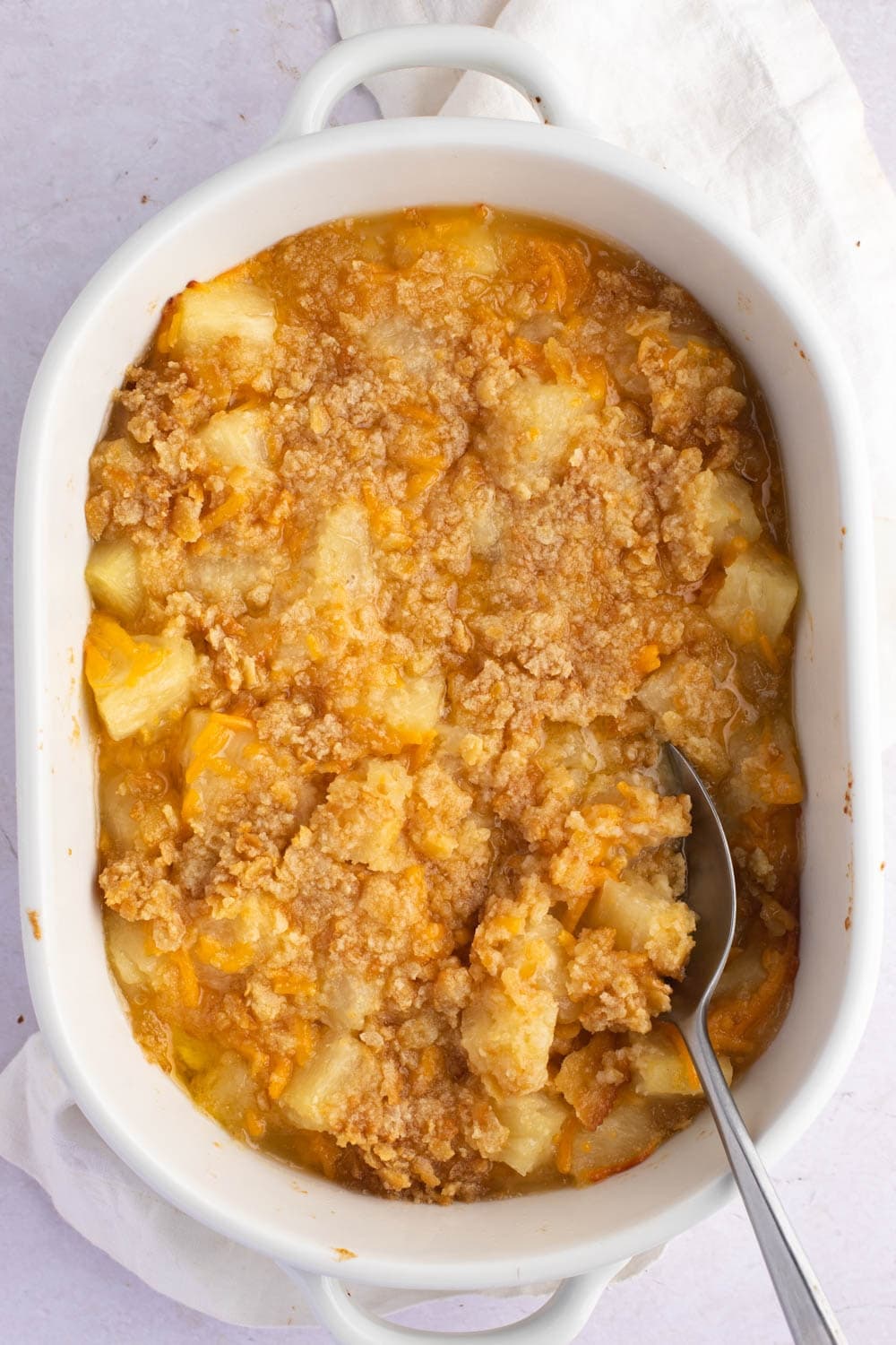 Top view of homemade Paula Deen pineapple casserole with a serving spoon.