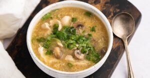 Homemade Tangy and Savory Hot and Sour Chicken Soup with Mushrooms in a White Bowl