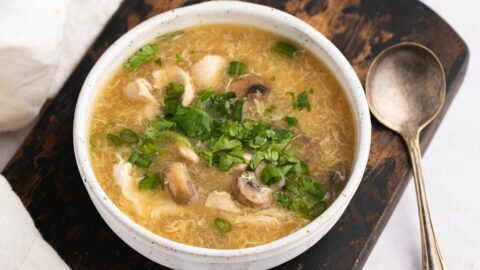 Homemade Tangy and Savory Hot and Sour Chicken Soup with Mushrooms in a White Bowl