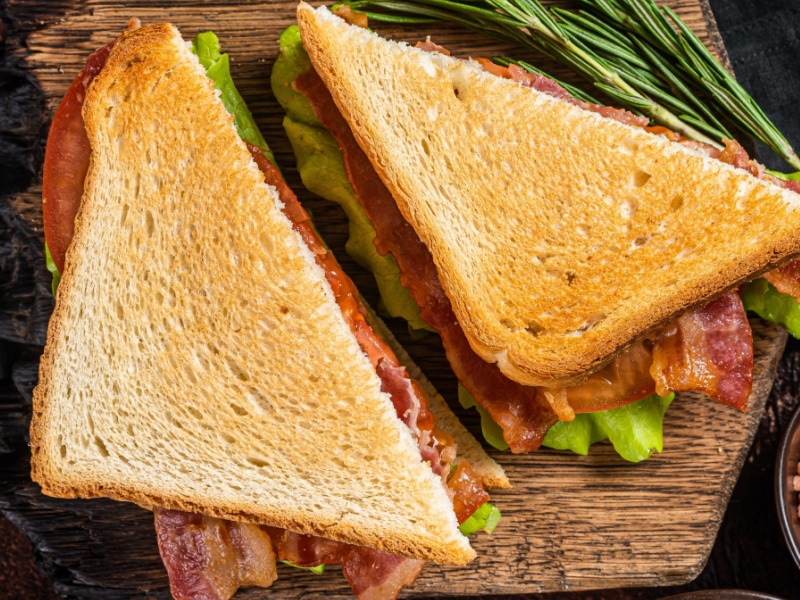 Pancetta Sandwich with Tomato and Lettuce on a Wooden Cutting Board
