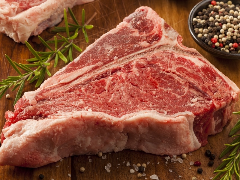 Raw Porterhouse with Salt and Pepper on a Wooden Table
