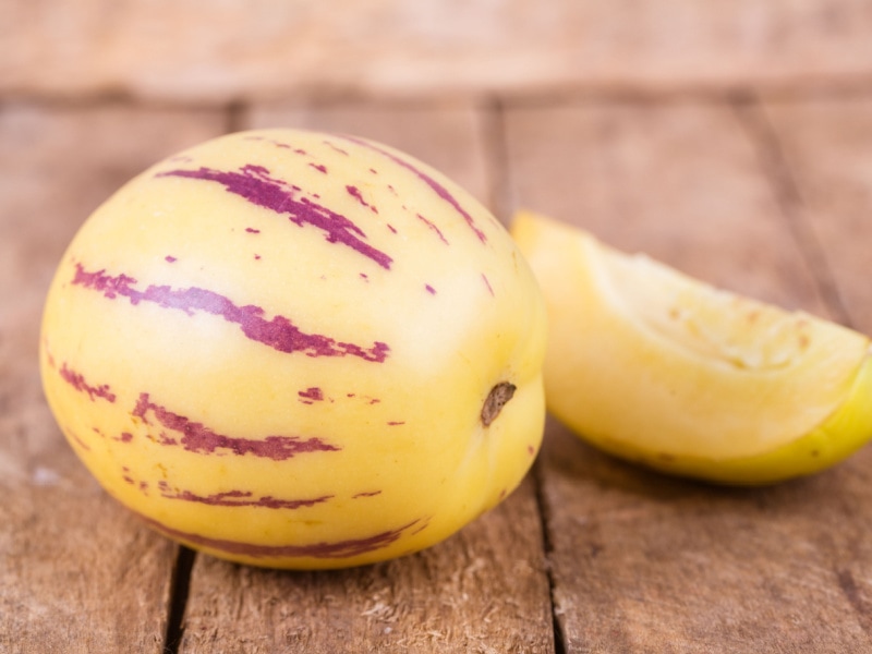 Whole and Slice of Ripe Pepino Melon on a Wooden Table
