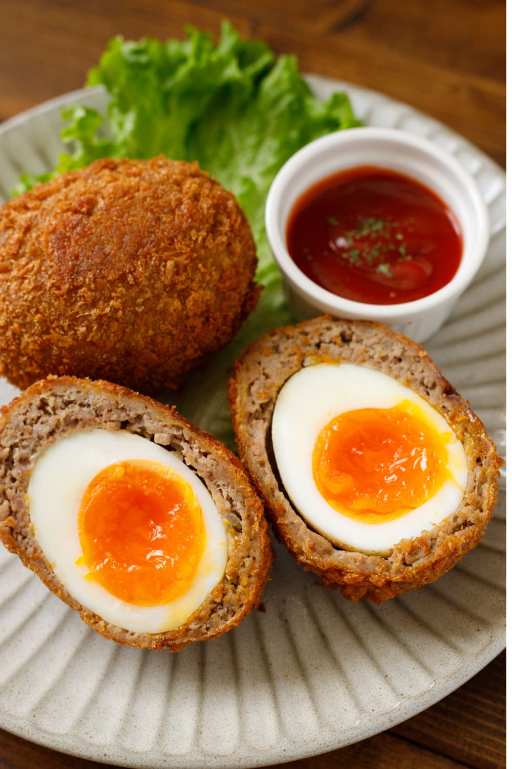 Breaded whole and sliced in half boiled eggs served with dip.