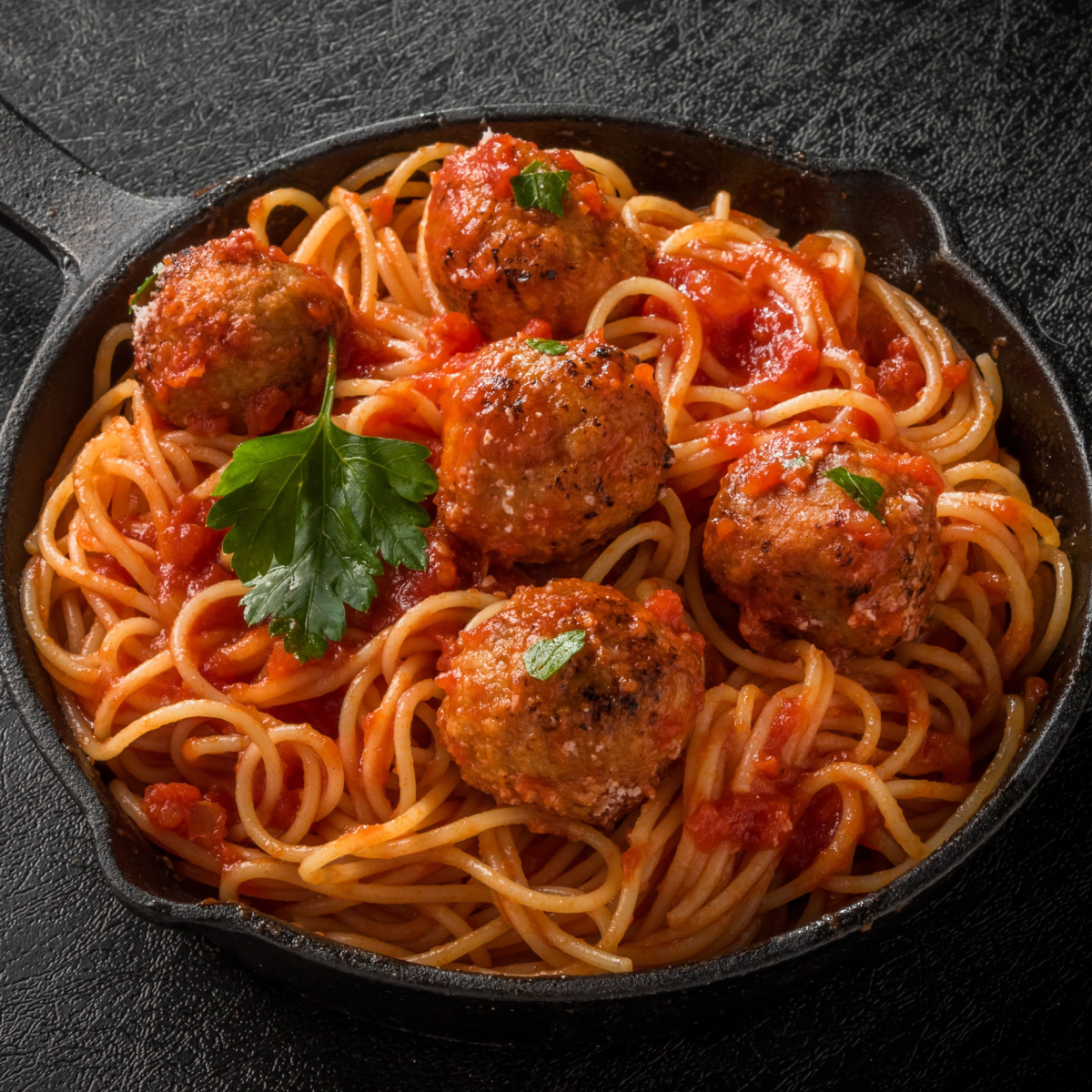 Spaghetti in Tomato Sauce and Meatballs in a Cast Iron Skillet with Fresh Herbs