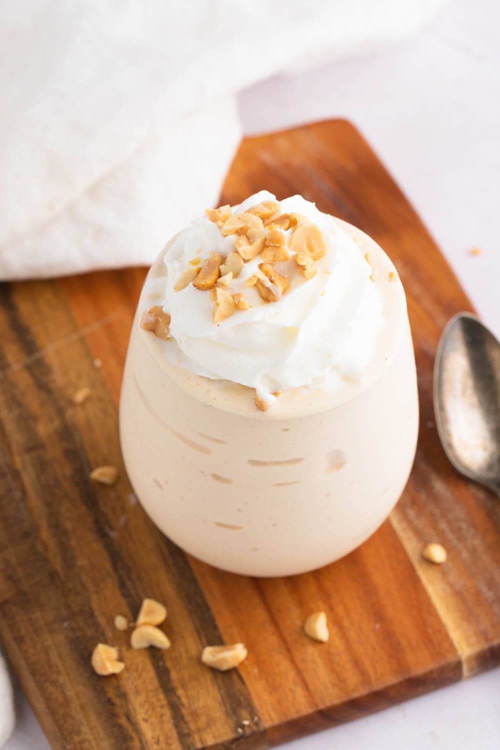 Peanut Butter Milkshake on a Glass Topped With Whipped Cream and Crushed Nuts