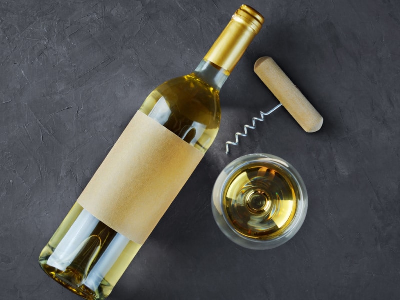 Bottle of Wine Lying on a Concrete Table with Glass and Cork Opener