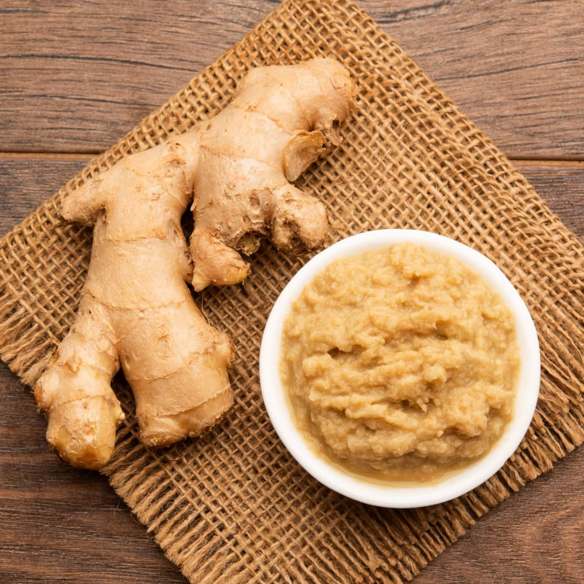 Ginger Whole Next to Ginger Paste on a Woven Cloth on a Wooden Table