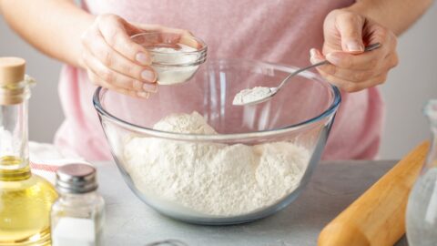 Woman Adding Baking Powder in a Glass Bowl