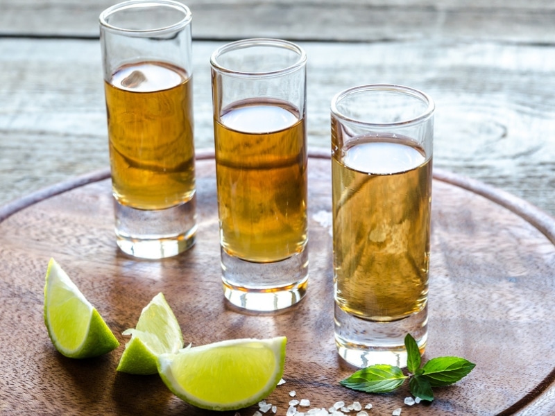 Three Tall Shot Glasses of Añejo Tequila With Slices of Lime and Salt