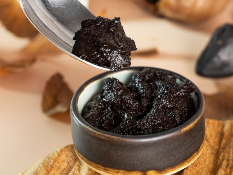 Creamy Black Garlic Paste on a Small Metallic Bowl, Scooped With a Spoon