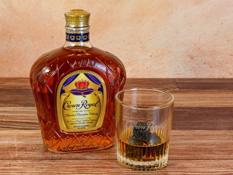 Crown Royal Blended Canadian Whisky Bottle and Glass With a Drink Over Whiskey Stones