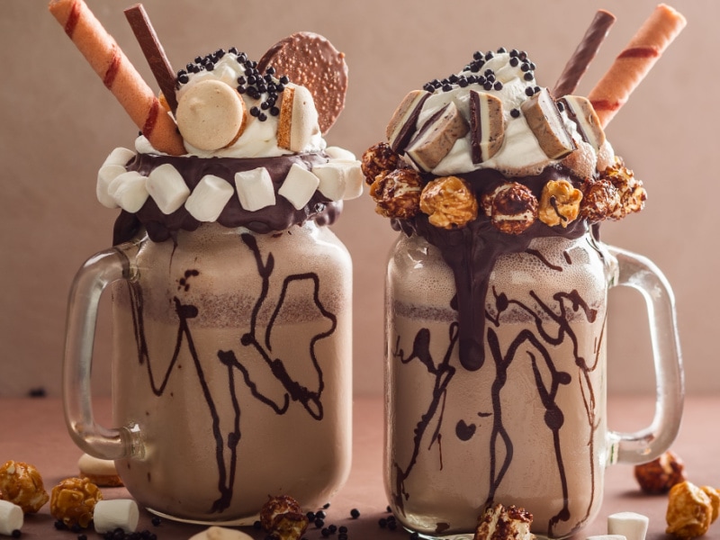 Monster Milkshakes in mason jars with marshmallows, popcorn, cookies, and whipped cream