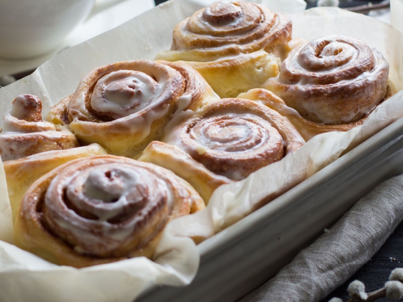 Cinnamon rolls in a ceramic baking dish with parchment paper lining