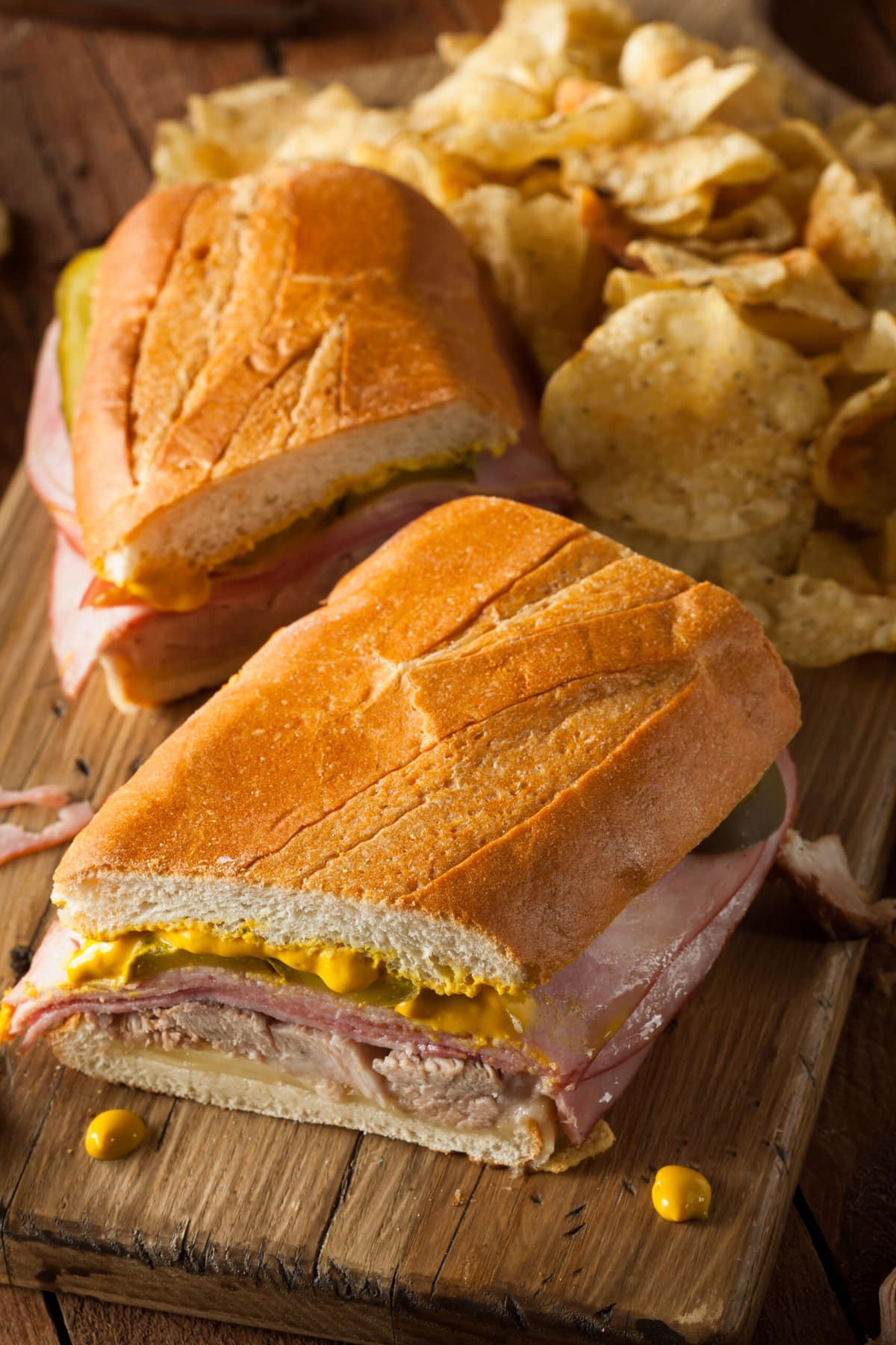 Sliced sandwich with Swiss cheese, ham, pulled pork, and pickles,