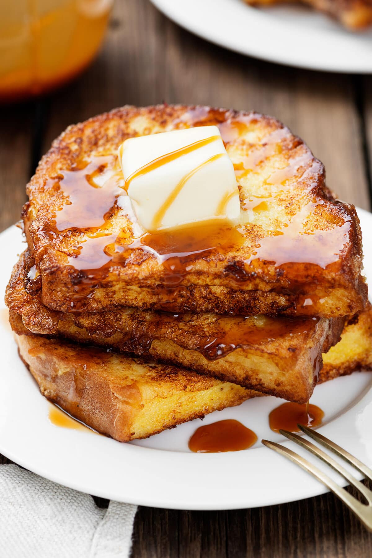 Eggnog French Toast served on a white plate with maple syrup and butter on top. 