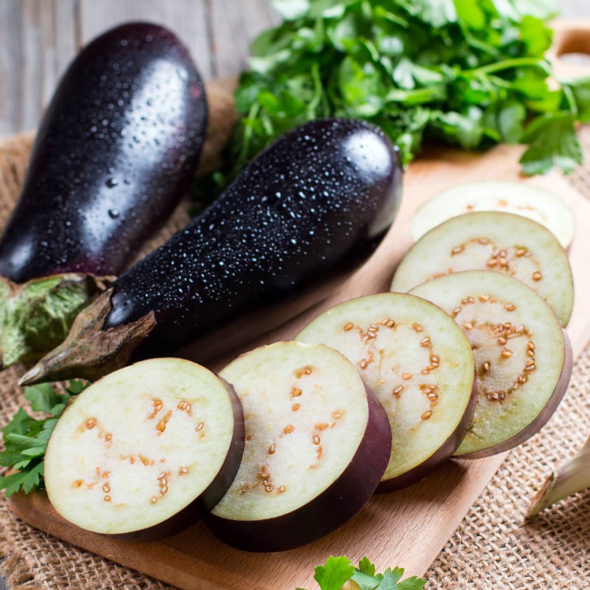 Whole and Slice Eggplant on a Wooden Cutting Board