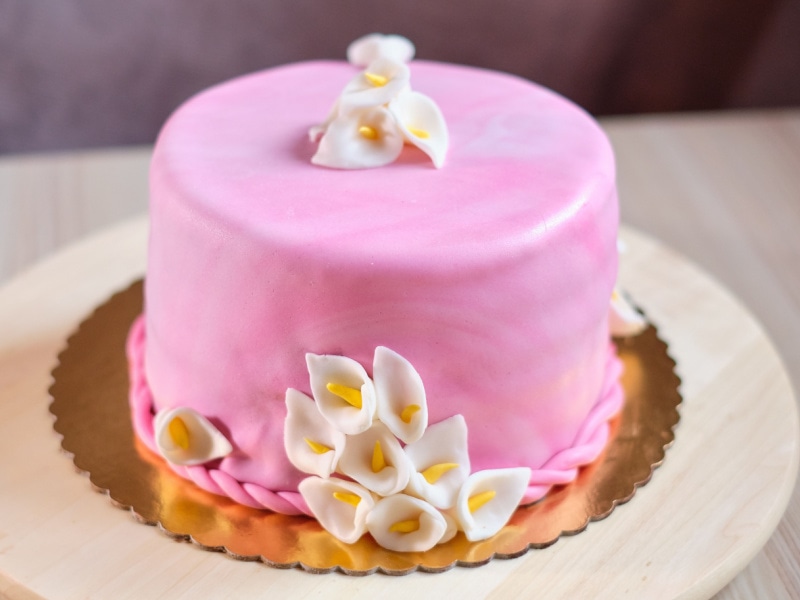 Round Pink Fondant-Covered Cake with Handmade Fondant Calla Lillies on a Fluted Gold Cake Board