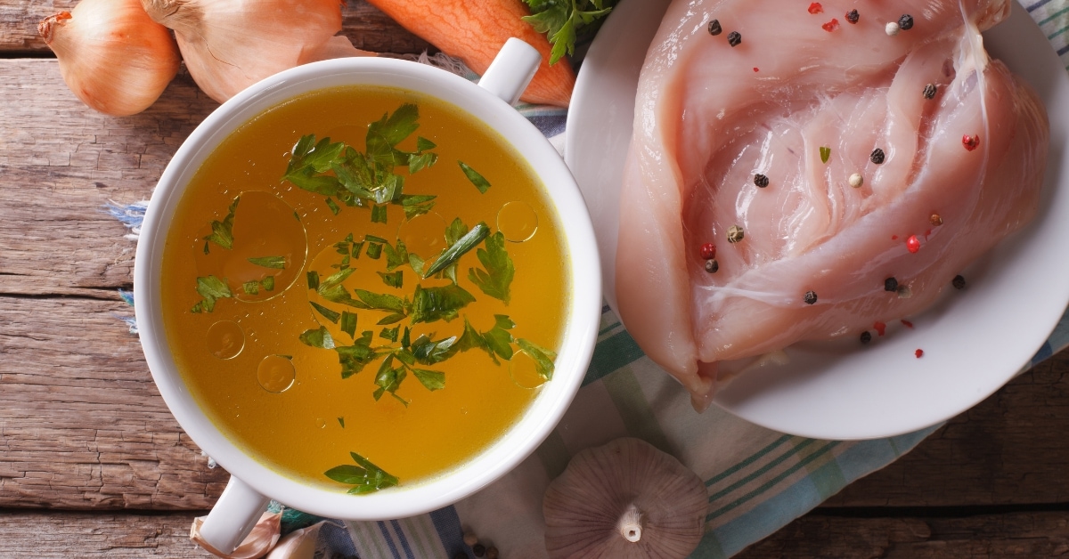Homemade Bowl of Chicken Broth with Raw Chicken
