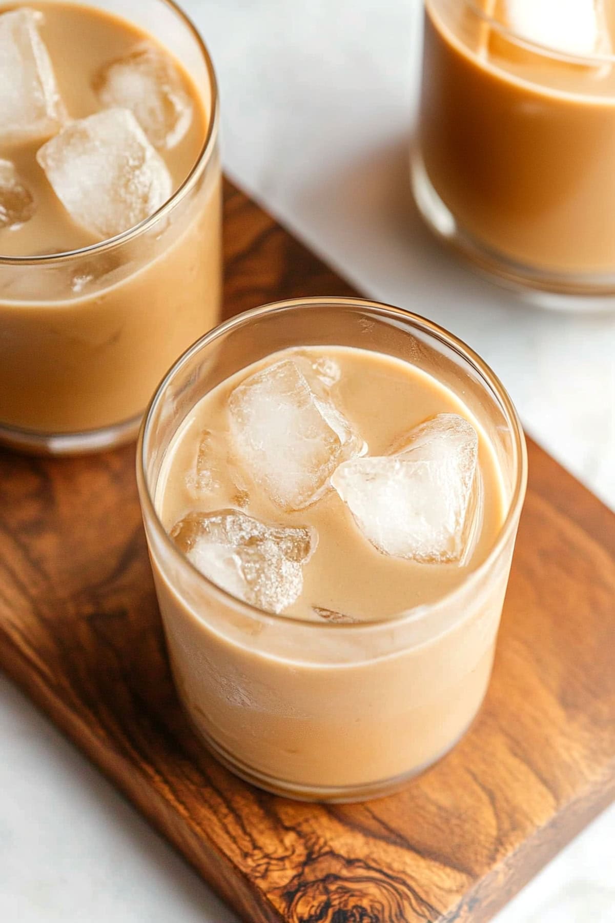 Homemade Irish Cream with a glass of ice on a wooden board.