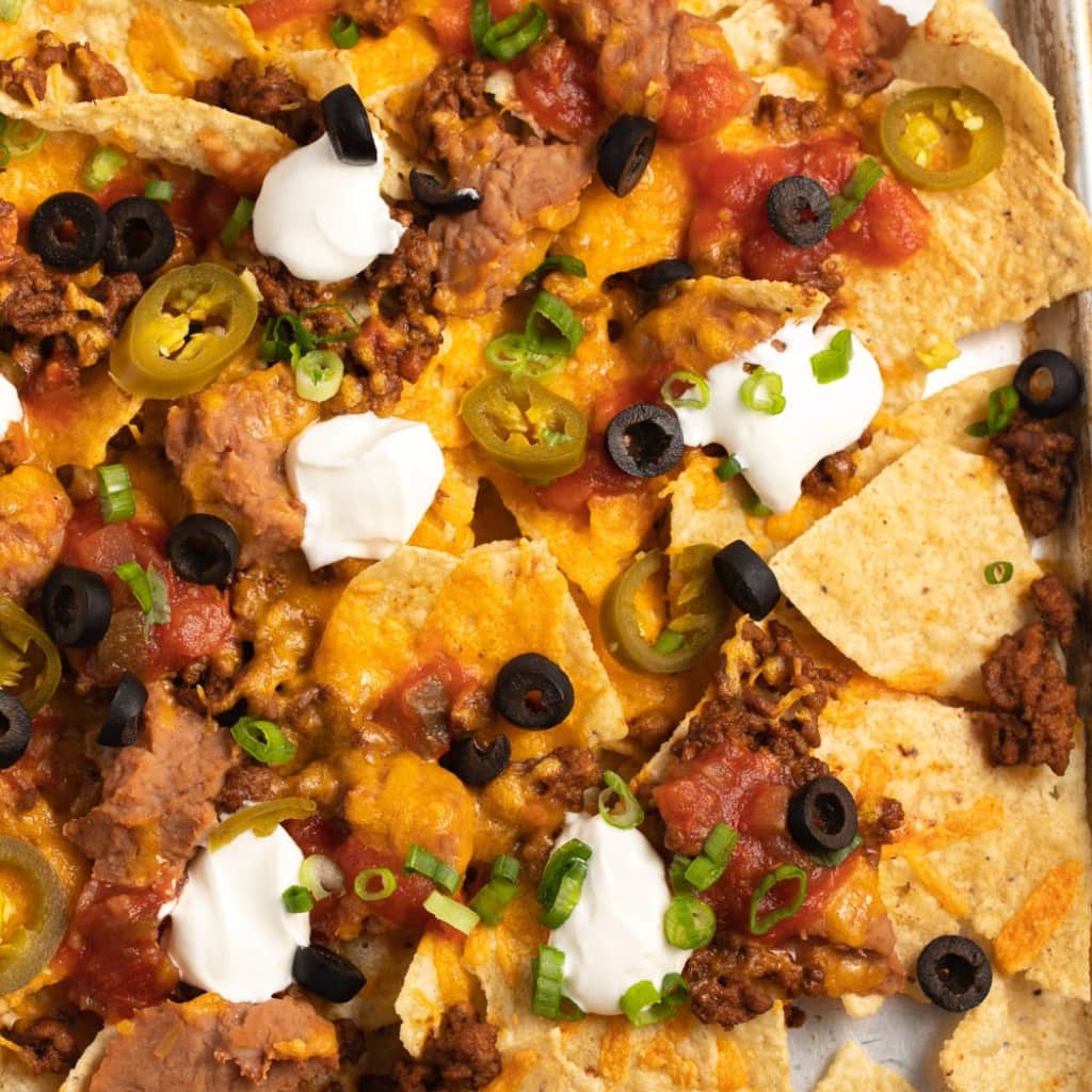 Taco nachos with ground beef, olives, salsa, chopped green onions and cheese