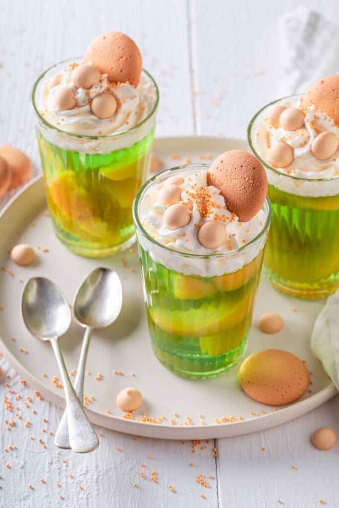 Fun Easter Jello Recipes featuring 3 Glasses Lime Jello With Orange Slices Topped With Whipped Cream, Candy, and Cookies