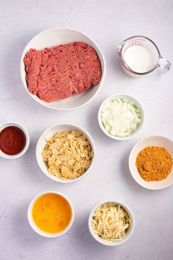 Mexican Meatloaf Ingredients - Onion, Crushed Tortilla Chips, Pepper Jack Cheese, Taco Mix, Eggs, Milk and Red Tomato Sauce