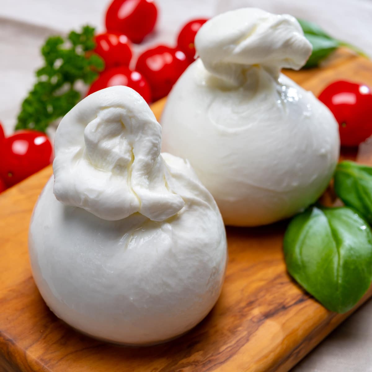 Two Rounded Balls of Mozzarella on a Wooden Cutting Board