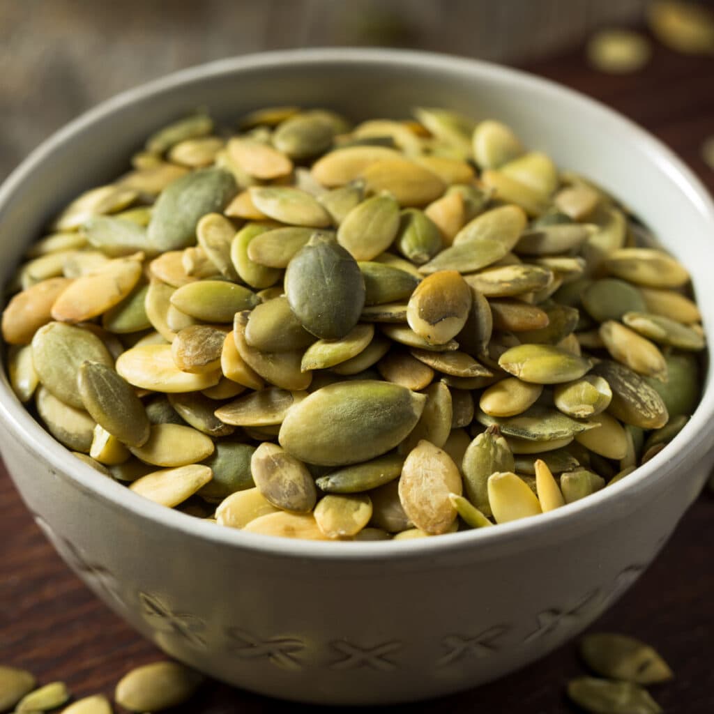 A Bowl of Raw Organic Pumpkin Seeds in a White Bowl