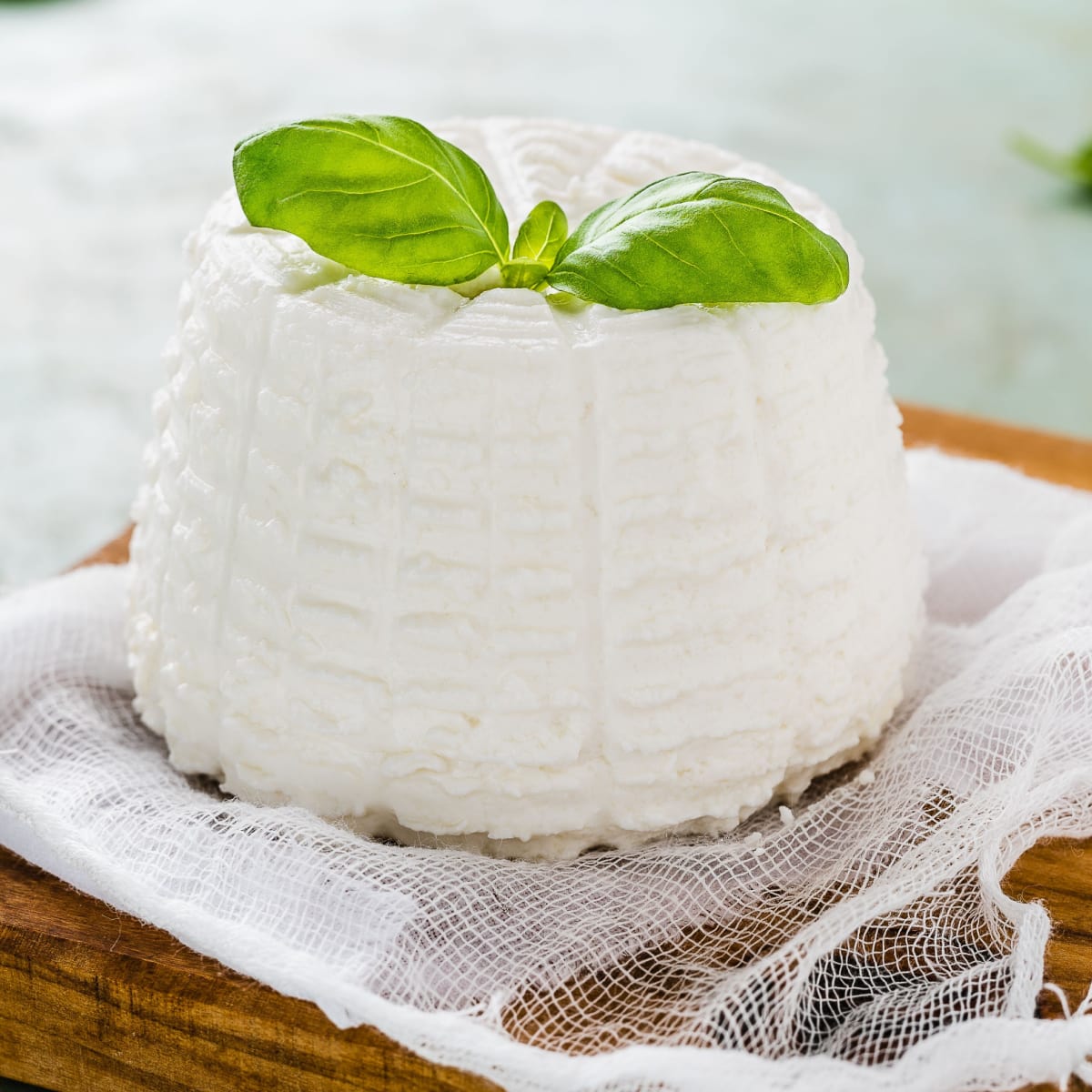 Ricotta Cheese with Basil on Top on a Wooden Cutting Board