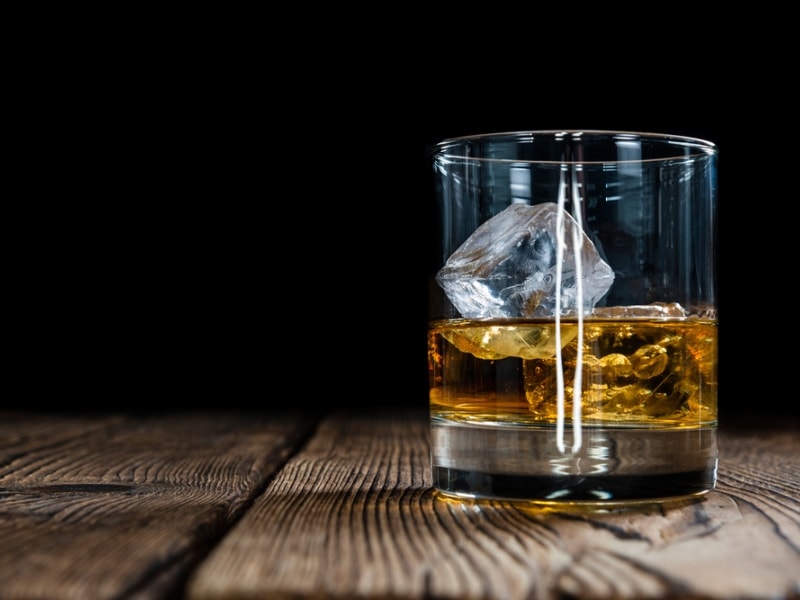 Single Malt Whiskey with Ice Cubes on Wooden Background