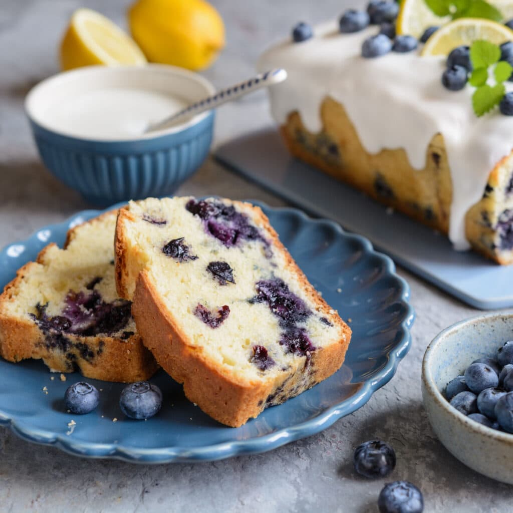 Fresh Blueberries in a Cup Beside a Lemon Blueberry Bread Slices Served in Blue Plate 