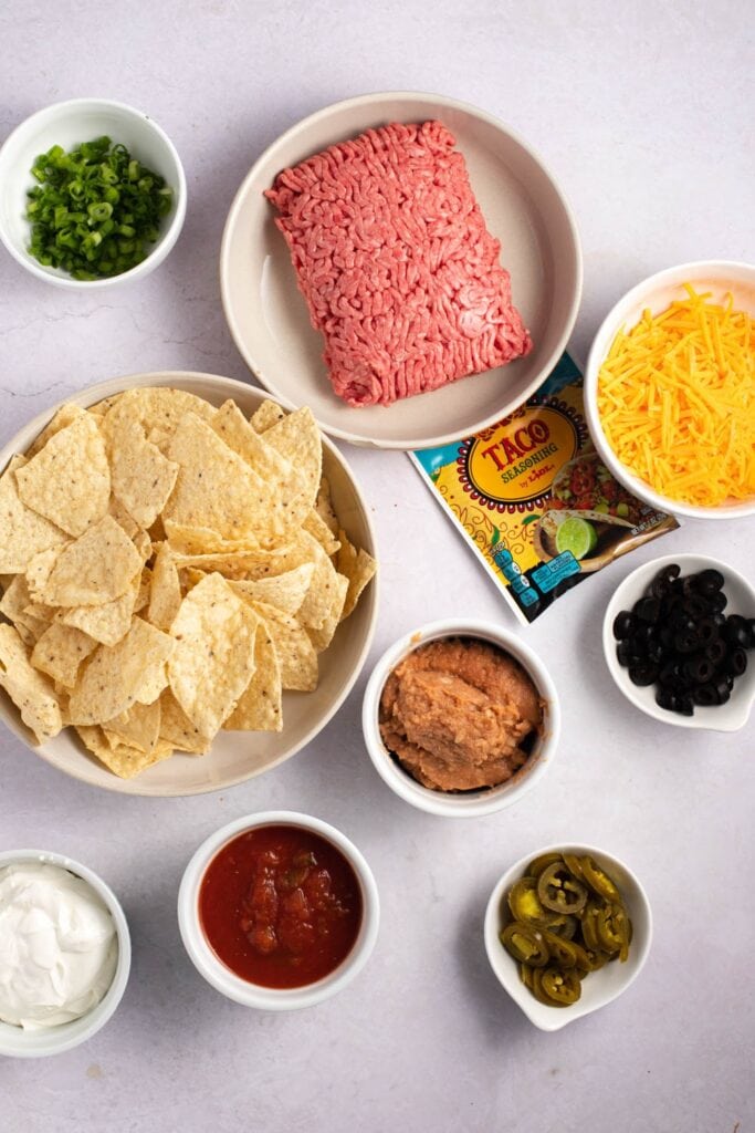Super Nachos Ingredients - Ground Beef, Tortilla Chips, Refried Beans, Black Olives, Salsa, Sour Cream, Jalapeno Peppers and Green Onions