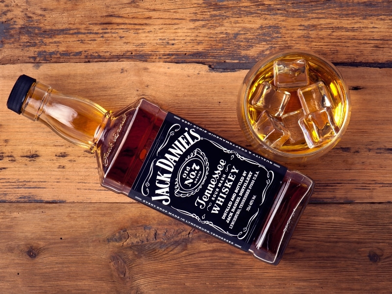 Bottle and a Glass of Iced of Jack Daniels Tennessee Whiskey on a Wooden Table