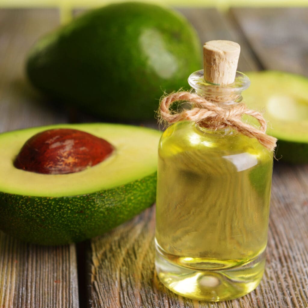 A Bottle of Avocado Oil and Fresh Avocado on a Wooden Table