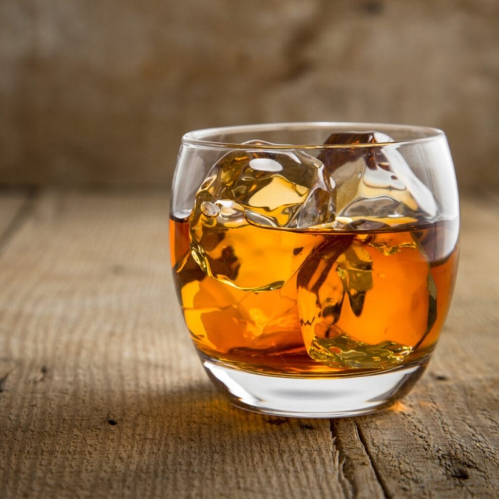 Glass of Bourbon over Ice on a Wooden Table