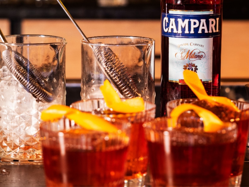 A Bottle of Campari and Cocktails on Glass