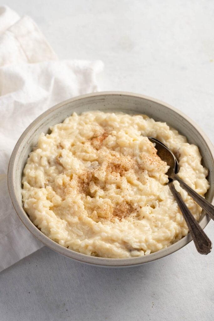 Deliciously Creamy Rice Pudding featuring Bowl of Creamy Rice Pudding with Cinnamon Sprinkles and Two Spoons