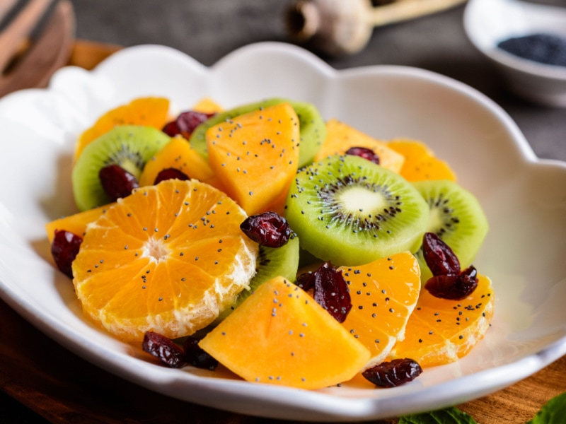 Fruit Salad with Tangelos, Kiwis, Mangos, and Dried Cranberries in a Fluted Bowl