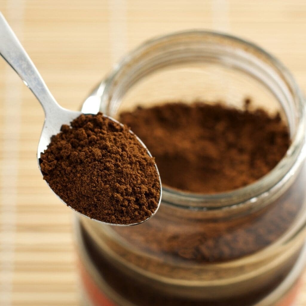 Teaspoon of Instant Coffee With an Opened Glass Jar in the Background