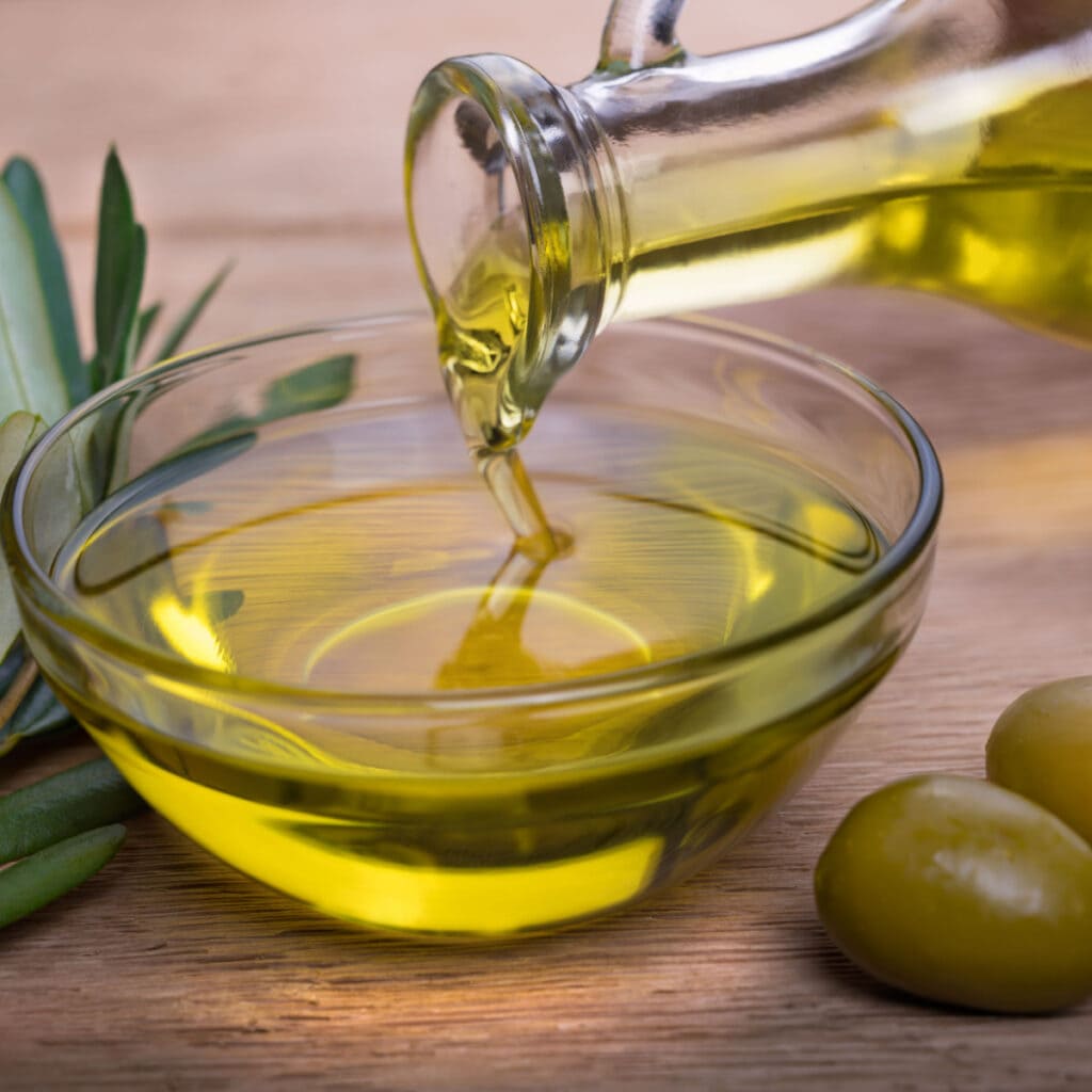 A Bowl of Olive Oil and Fresh Olives on a Wooden Table