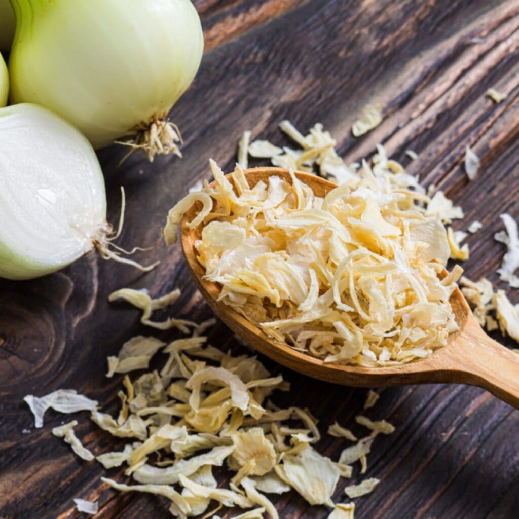 Peeled White Onions and Onion Flakes on a Wooden Table