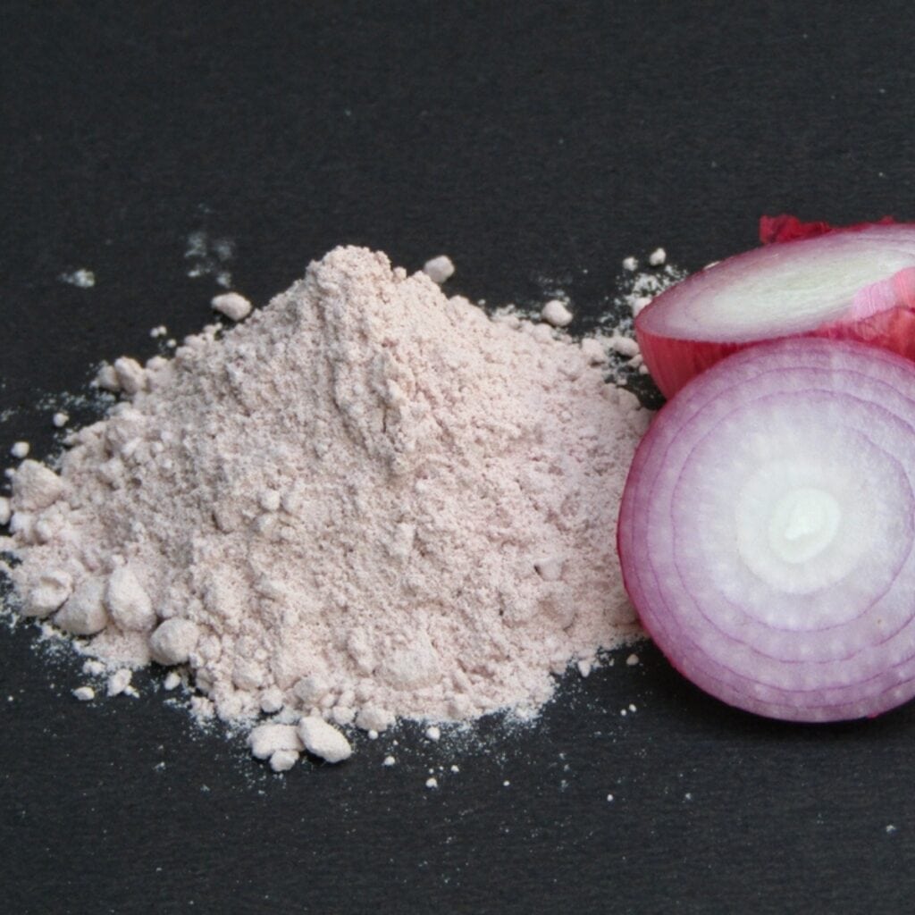 Onion Powder and Sliced Onions on a Black Table Surface