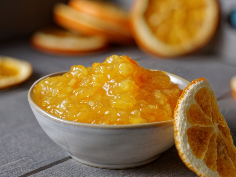 A Bowl of Orange Marmalade and Dried Orange Slice with Dried Orange Slices in the Background