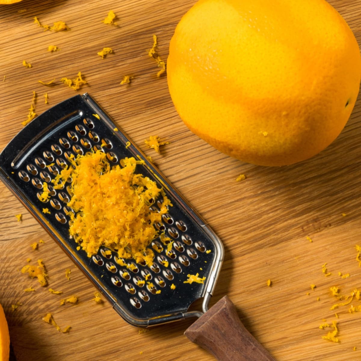 Fresh Orange, Zested With a Grater on a Wooden Cutting Board