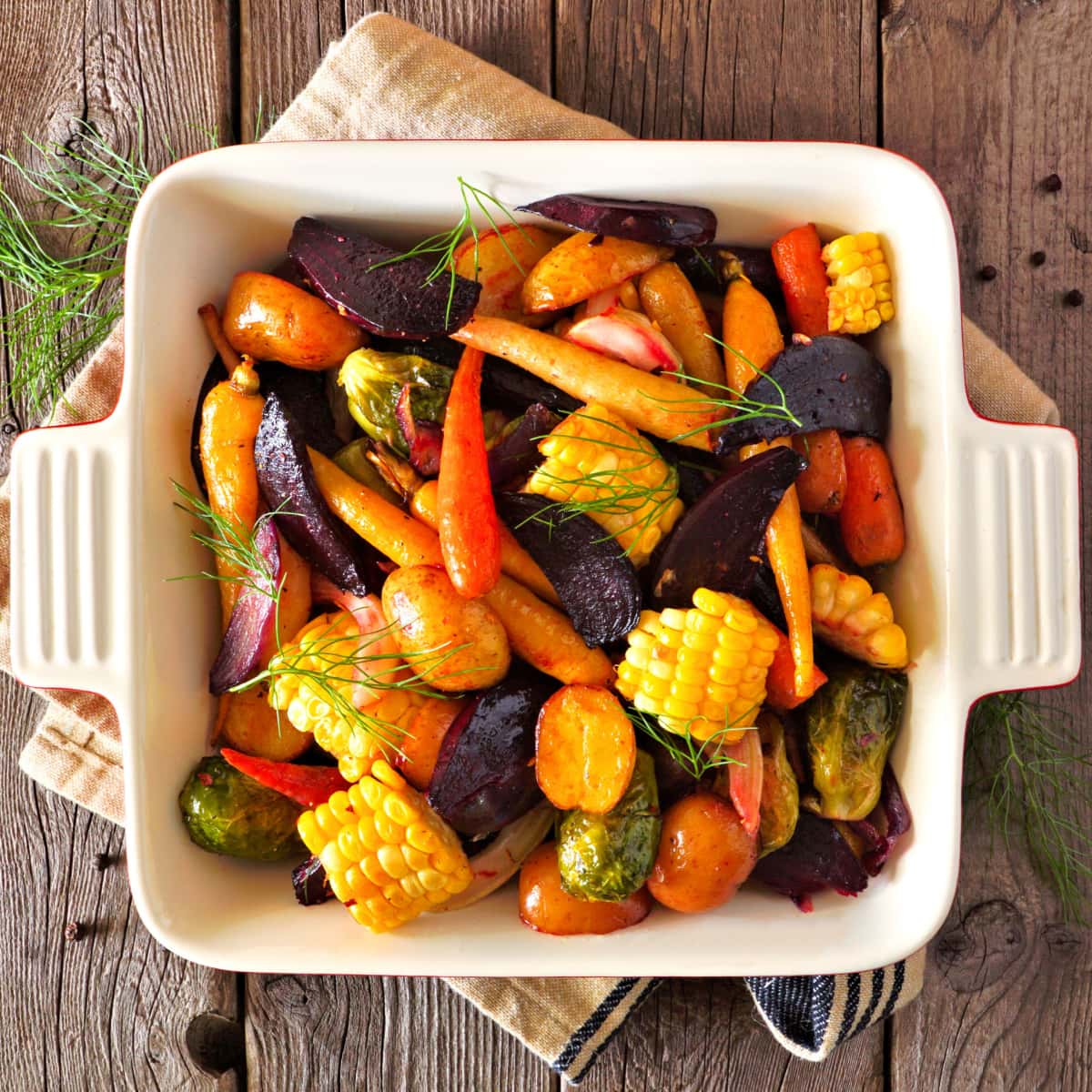 Roasted bell peppers, carrots, broccoli, asparagus, and corn on a casserole dish. 