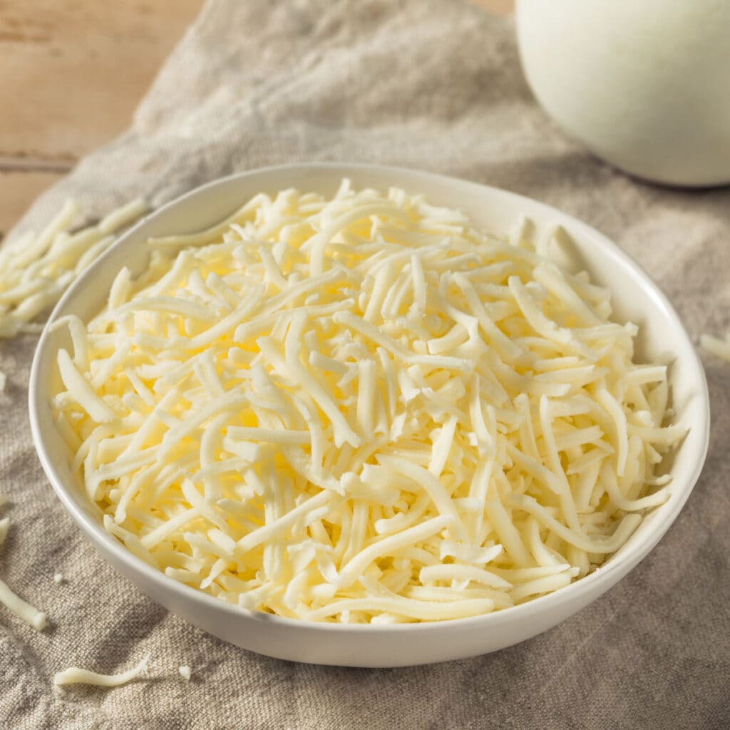 A Bowl of Shredded Cheese on a Wooden Table